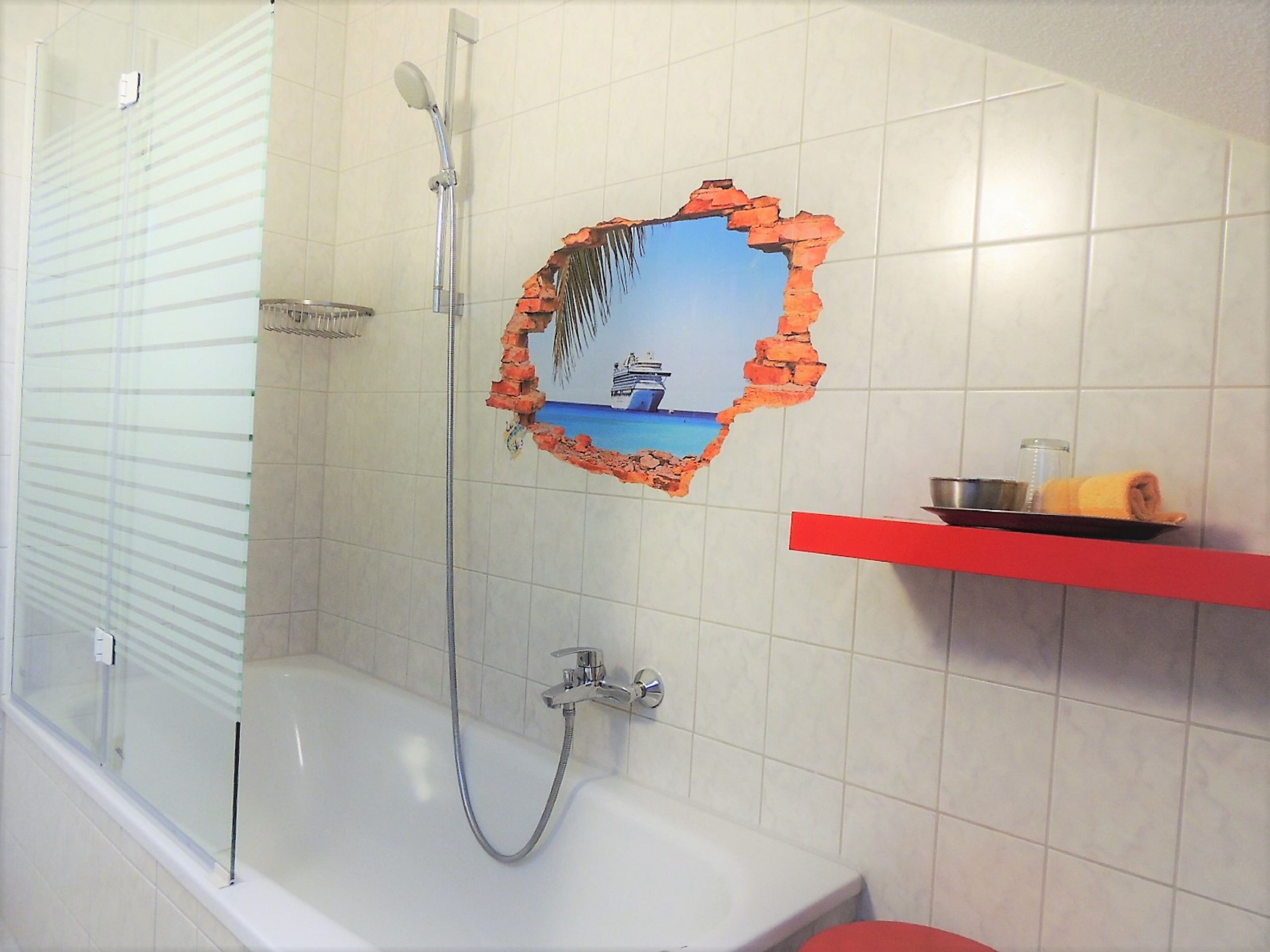 Une salle de bain avec une douche, une baignoire et une étagère rouge sur laquelle est posée une serviette.