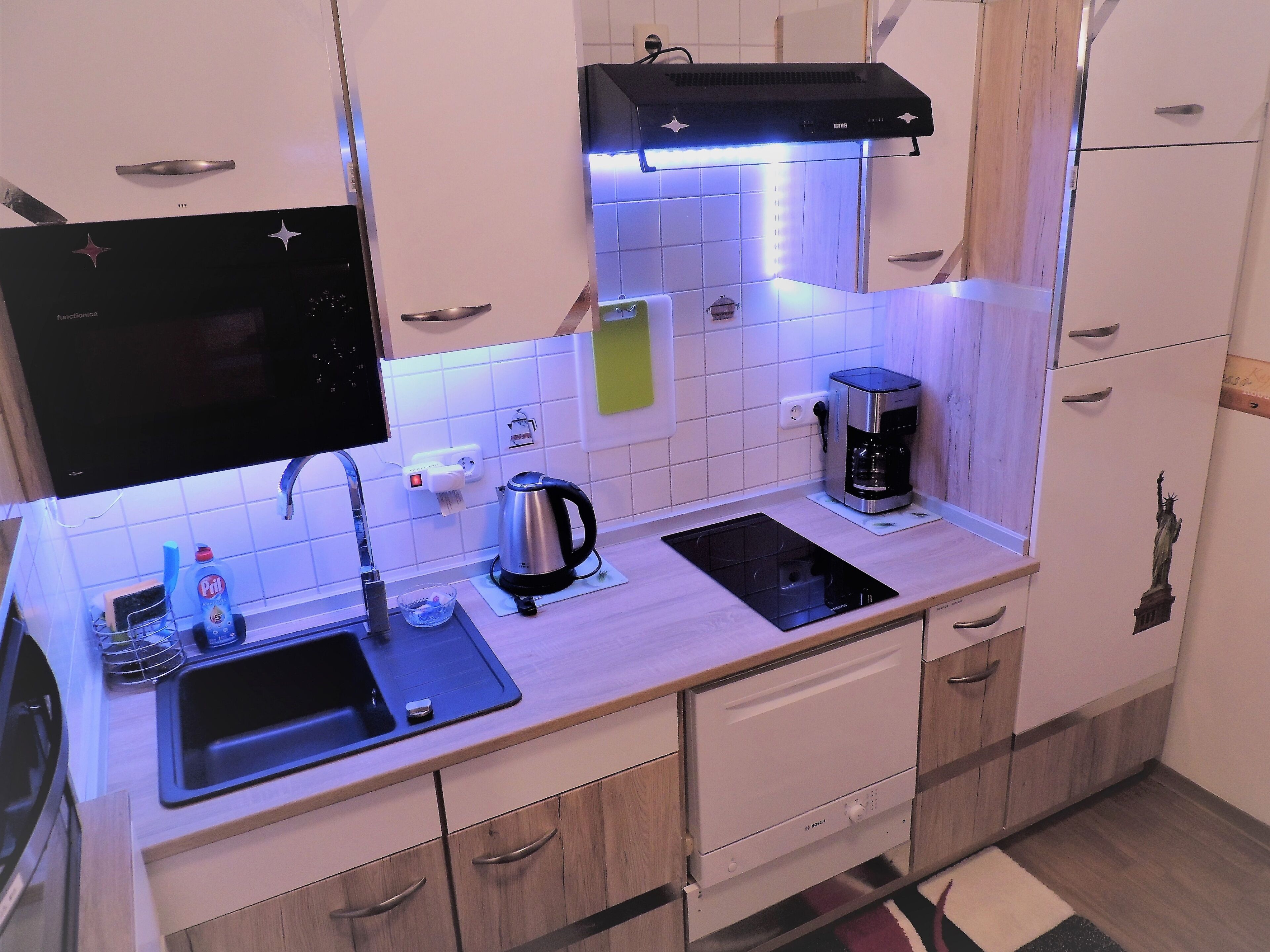 A modern kitchen with a built-in stove, a coffee maker, and a kettle on the countertop.