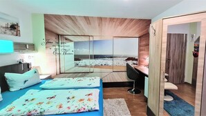 Ein Zimmer mit Bett, Schreibtisch und Blick auf den Strand durch einen großen Spiegel.