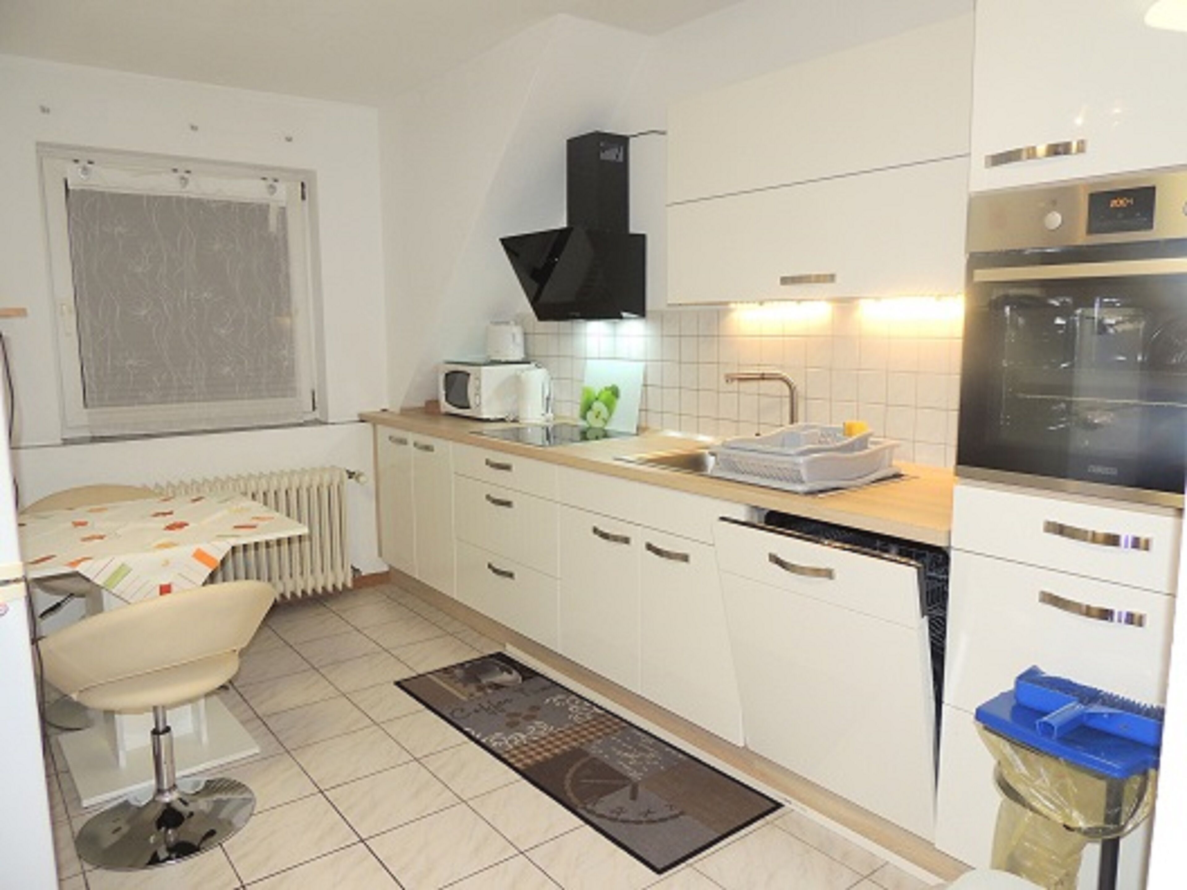 A compact kitchen with white cabinets, a microwave, a sink, and a stove.