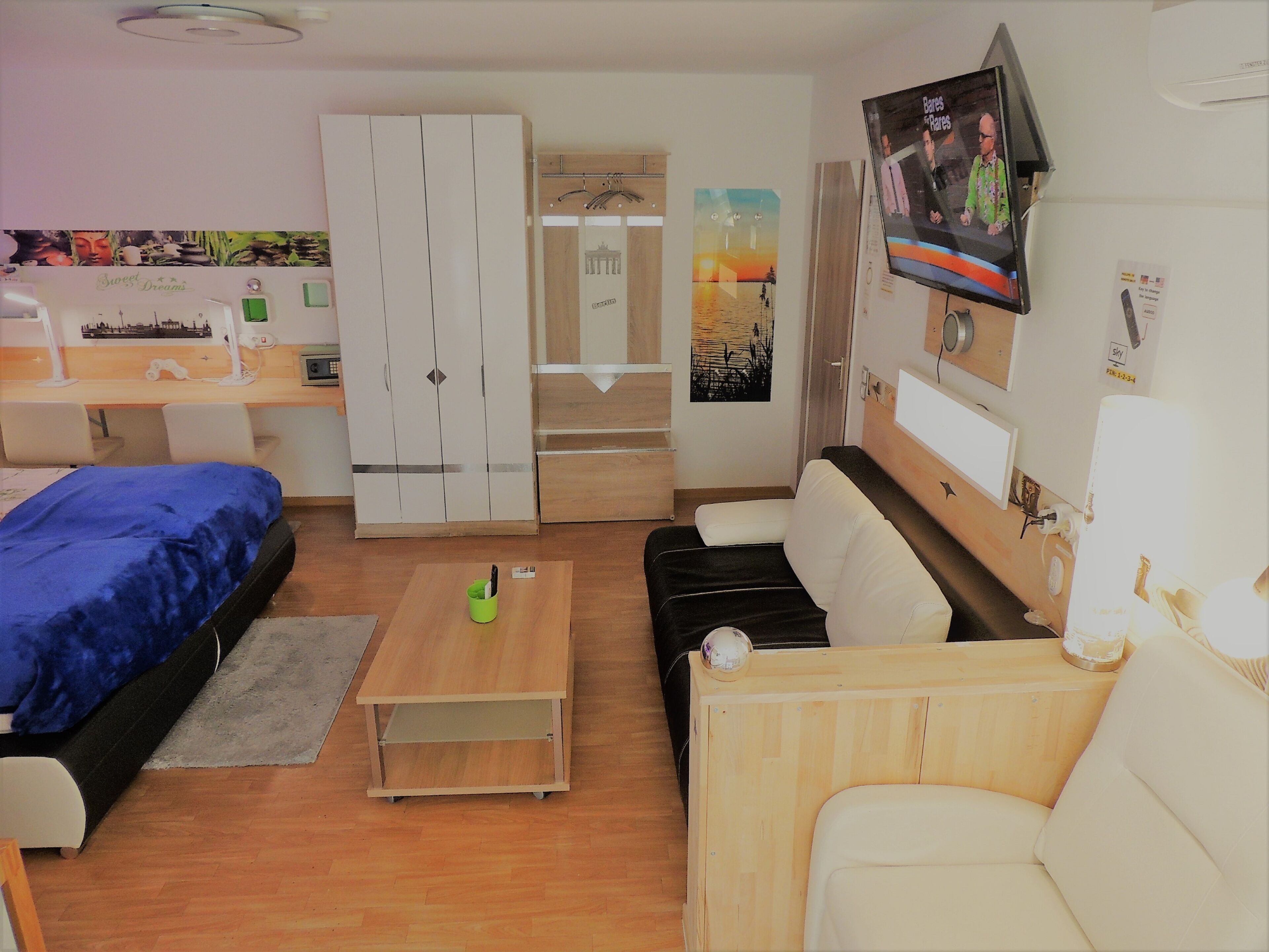 Habitación de hotel pequeña con cama, escritorio, silla, sofá y televisor.