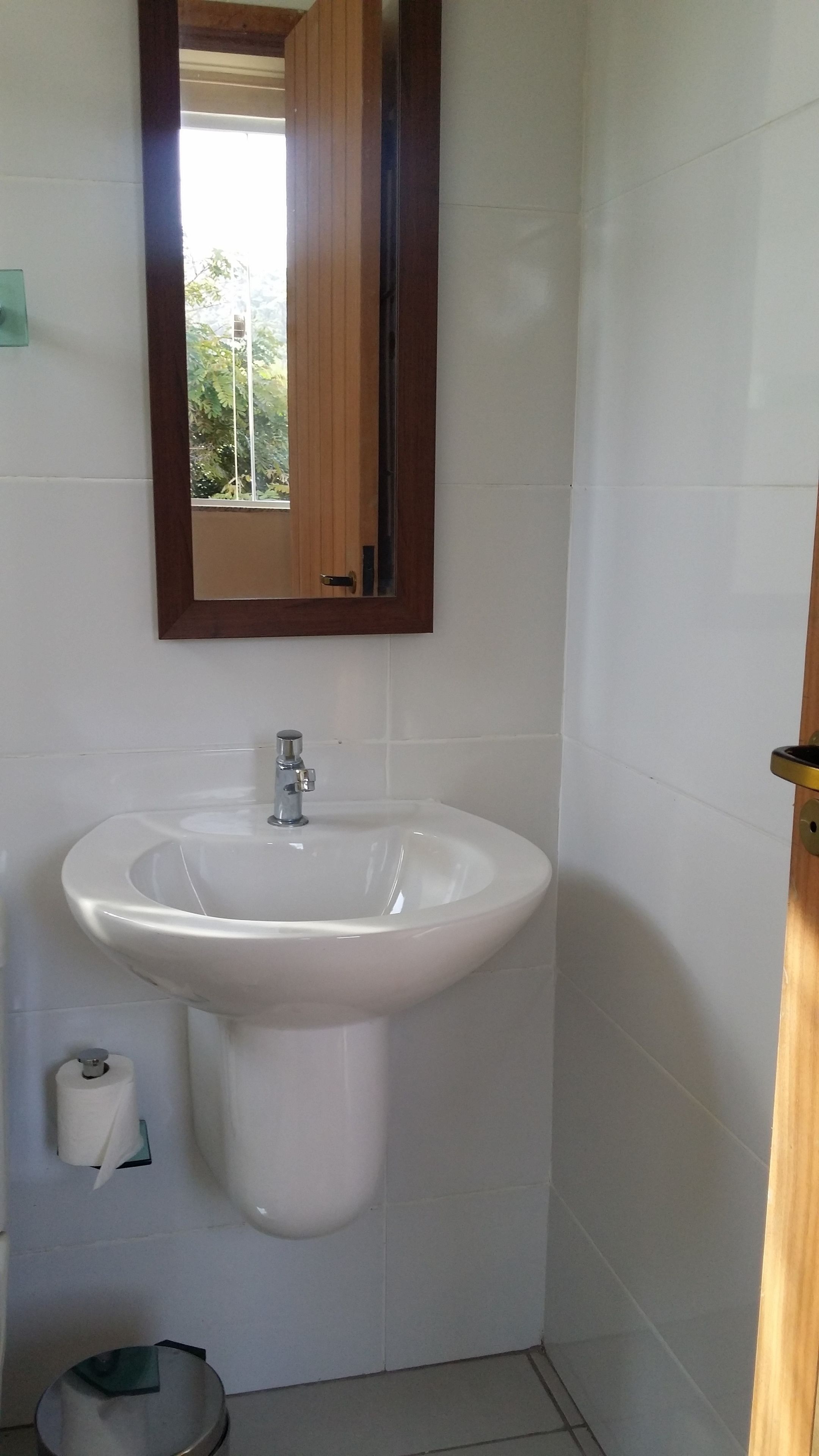 Un baño con lavamanos blanco, espejo y retrete.