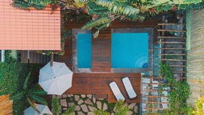 Un área de piscina en la azotea con dos piscinas, sillas de descanso y una terraza de madera.