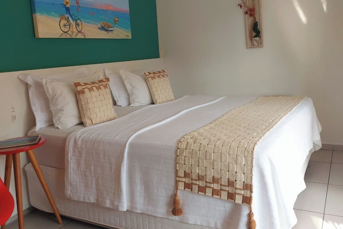 A neatly arranged bedroom with a bed, a small table, and a painting on the wall.