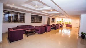 A spacious lobby with a high ceiling, recessed lighting, and a seating area with purple sofas. - Hotel Menino Executive (Ponda)