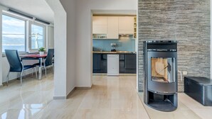 Une cuisine moderne dotée d’une cuisinière intégrée, un coin repas avec une table et des chaises, et une vue sur la mer grâce à de grandes fenêtres.