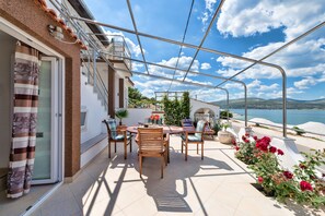 Une terrasse avec une table et des chaises, un pot de fleurs et une vue sur la mer.