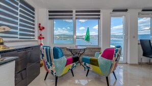 Une cuisine moderne avec vue sur la mer, deux chaises colorées et une table à manger.