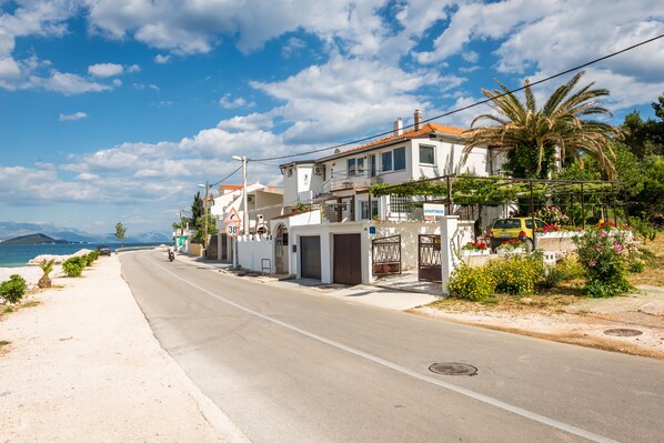 Une route côtière bordée de maisons, un ciel dégagé et une vue sur la mer.