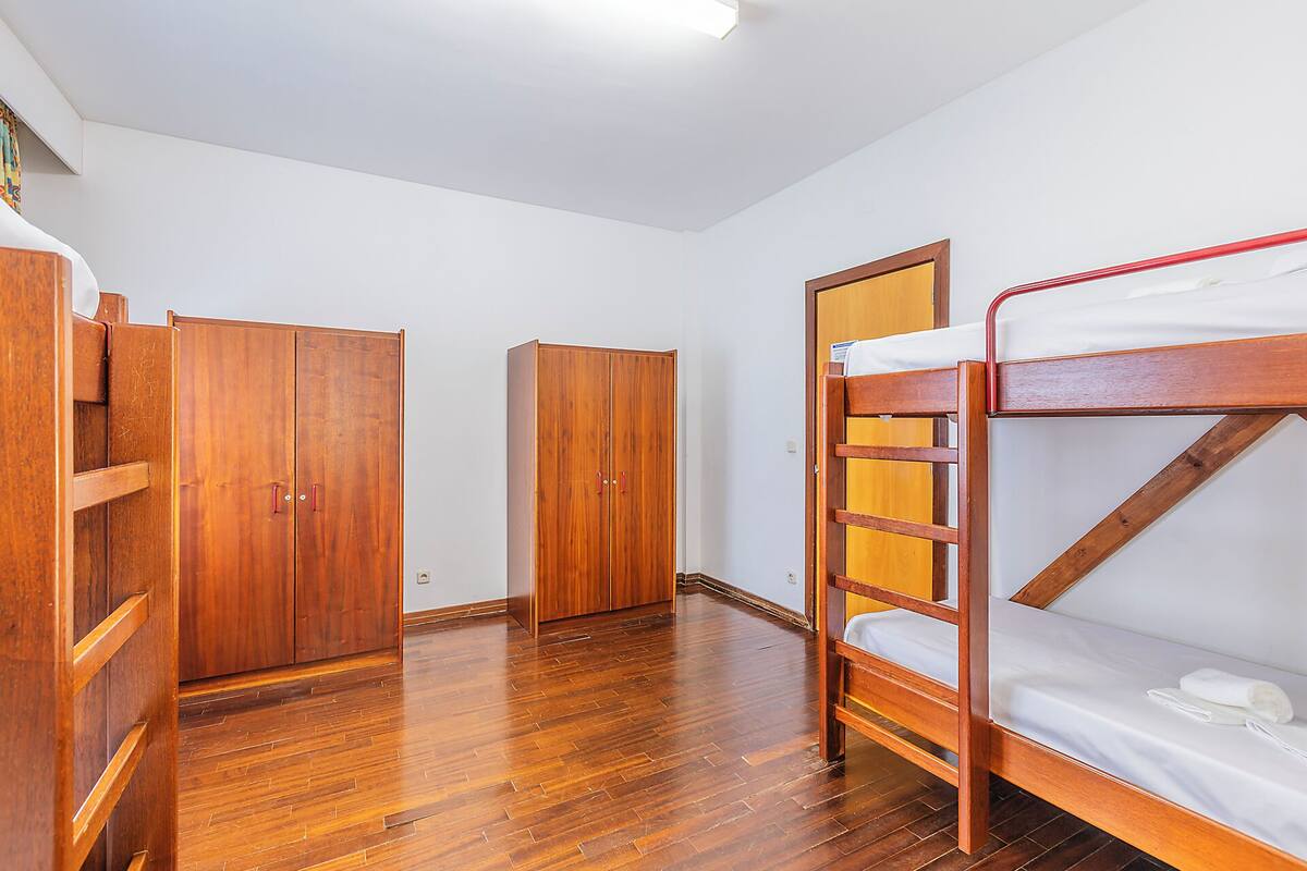 A room with wooden bunk beds, a wardrobe, and a door.