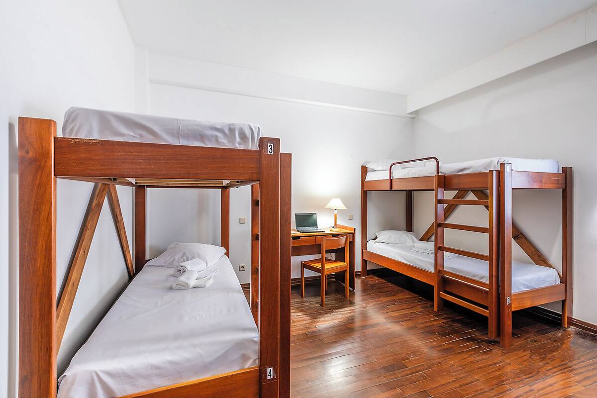 A room with two bunk beds, a desk with a laptop, and a chair.