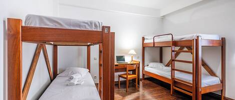 A room with two bunk beds, a desk with a laptop, and a chair.