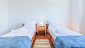 A twin room with two beds, a nightstand with a lamp, and a wooden floor. - HI Foz Côa - Pousada de Juventude - Hostel (Vila Nova de Foz Coa)