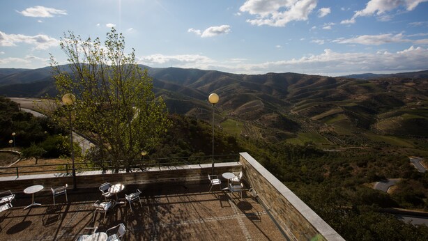 A terrace with outdoor seating and a view of rolling hills. - HI Foz Côa - Pousada de Juventude - Hostel (Vila Nova de Foz Coa)