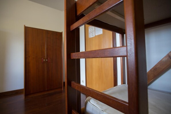 A wooden staircase with a handrail and a view of a wooden door in the background.