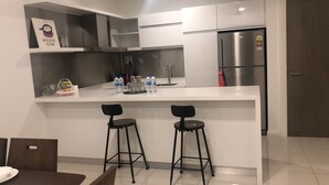 Una cocina moderna con un refrigerador de acero inoxidable, una encimera blanca y dos taburetes negros.