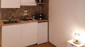 A compact kitchen with white cabinets, a built-in sink, and a small countertop. - B&B Le Rose (Salerno)