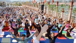 Un grupo grande de personas realizando una actividad sincronizada de ejercicio o yoga al aire libre.