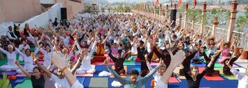 A large group of people performing a synchronized exercise or yoga session outdoors.