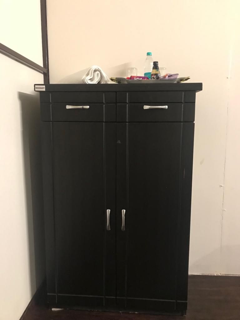 Guarda-roupa preto com duas portas e duas gavetas, cada uma com puxador prateado.