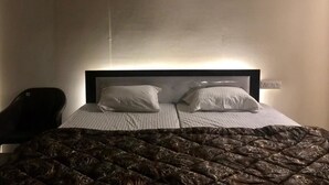 Habitación de hotel con cama, dos almohadas, cabecera, una obra de arte en la pared y una silla.