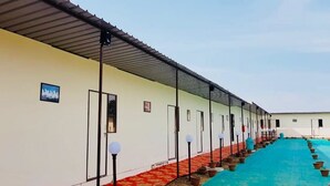 Filas de habitaciones de hotel con puertas individuales, un paseo techado y una zona de piscina.