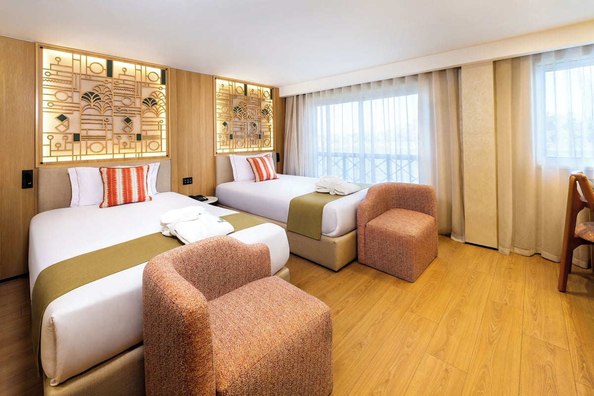 A hotel room with two beds, a seating area, and a decorative wall panel.