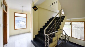 Una escalera con barandilla de metal, un cartel de seguridad CCTV y un amplio ventanal con vistas a edificios.