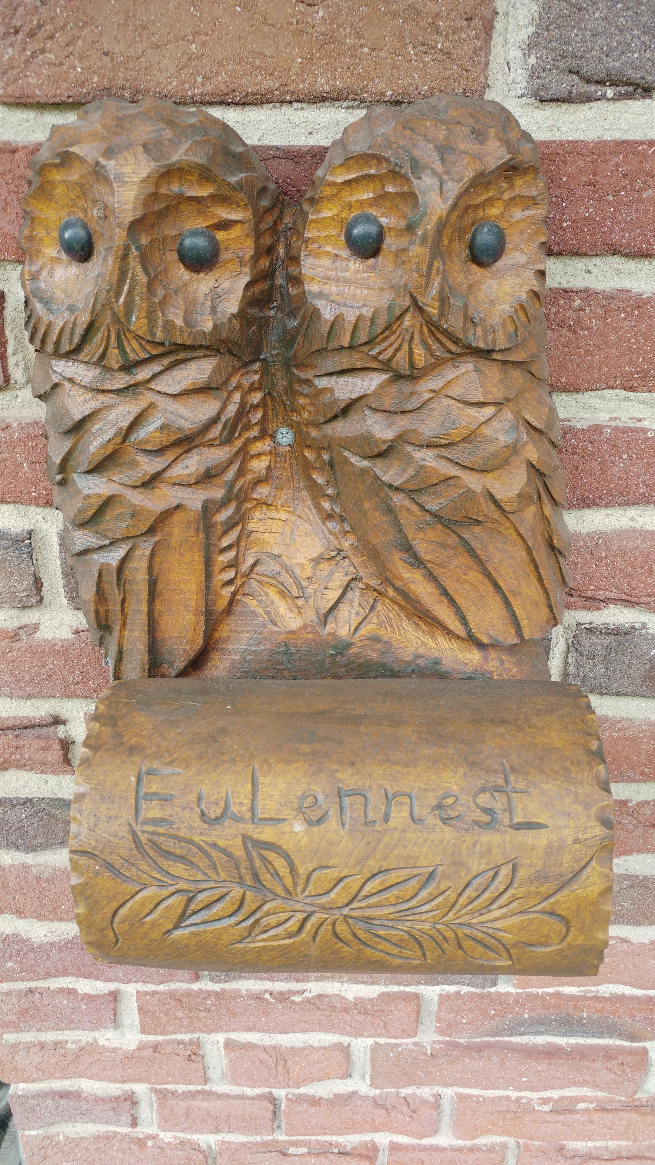 Una placa de fusta amb un autet i la inscripció "Eulennest" sobre un mur de maó.