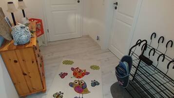 A hallway with a wooden bench, a colorful rug with bird and butterfly designs, and a coat rack.