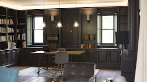 A library with bookshelves, a desk, and a chair. - Arambrook Boutique Hotel (Cape Town)