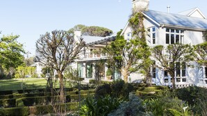 A large, white, two-story house with a well-manicured garden, including hedges and trees. - Arambrook Boutique Hotel (Cape Town)