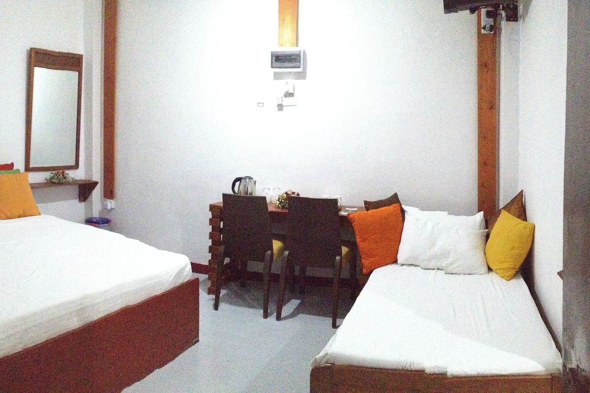 A hotel room with two beds, a desk, and a chair.