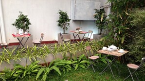 An outdoor seating area with tables and chairs, surrounded by potted plants and ferns. - Cinnamon Airport Residencies (Seeduwa - Katunayake)