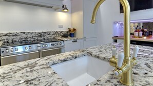 A kitchen with a granite countertop, stainless steel appliances, and a gold faucet. - The Tannochbrae (Keith)