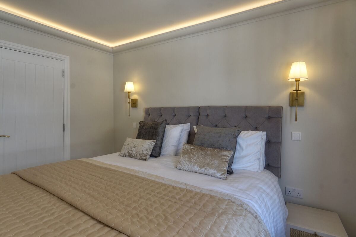 A bedroom with a large bed, two wall-mounted lamps, and a white door.