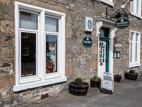 A stone building with a sign for Tannochbrae Guest House and Restaurant, a sign for a sky bar, and a sign indicating vacancies. - The Tannochbrae (Keith)
