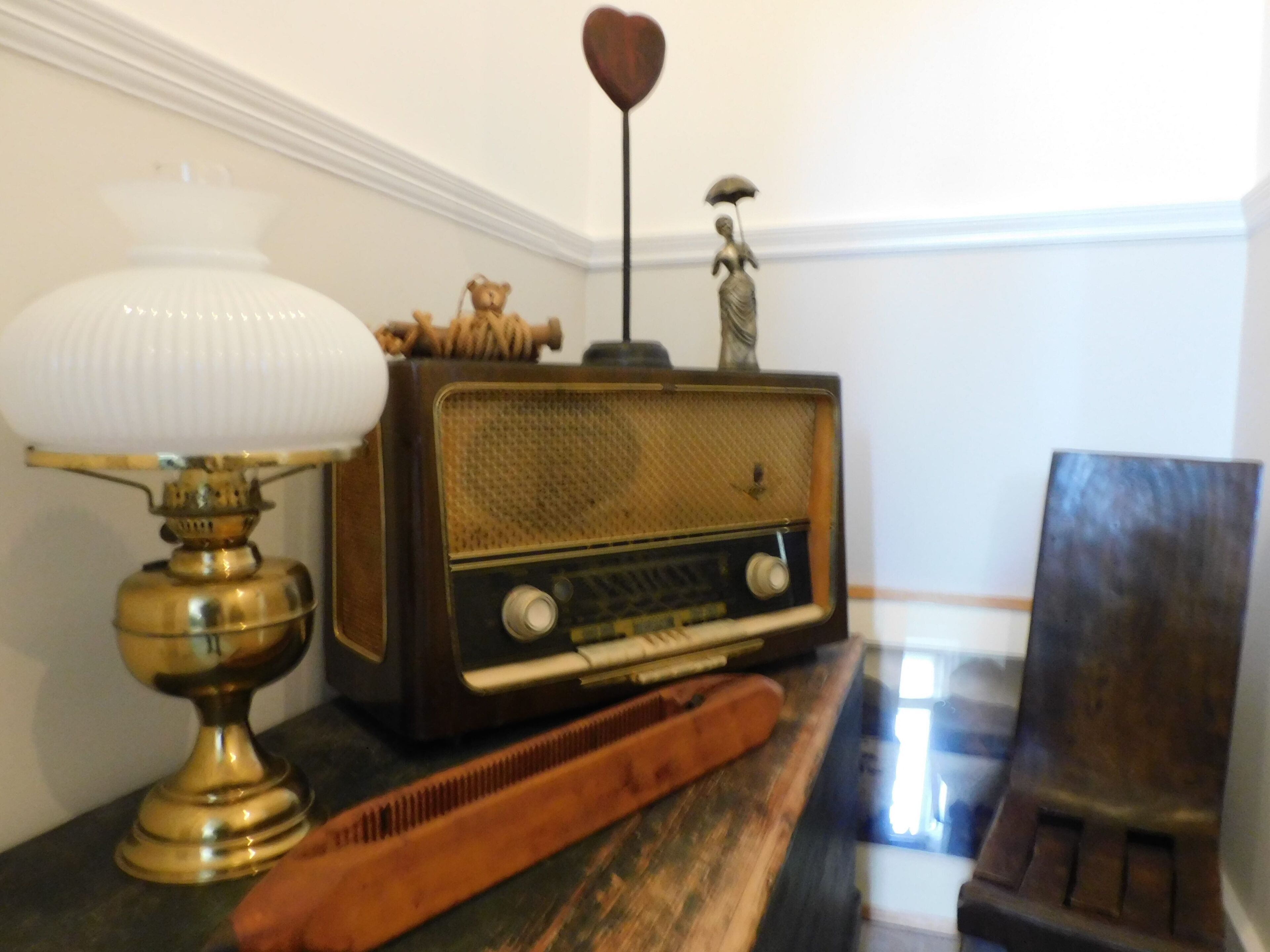Une radio ancienne, une lampe et un peigne, posés sur une surface en bois.