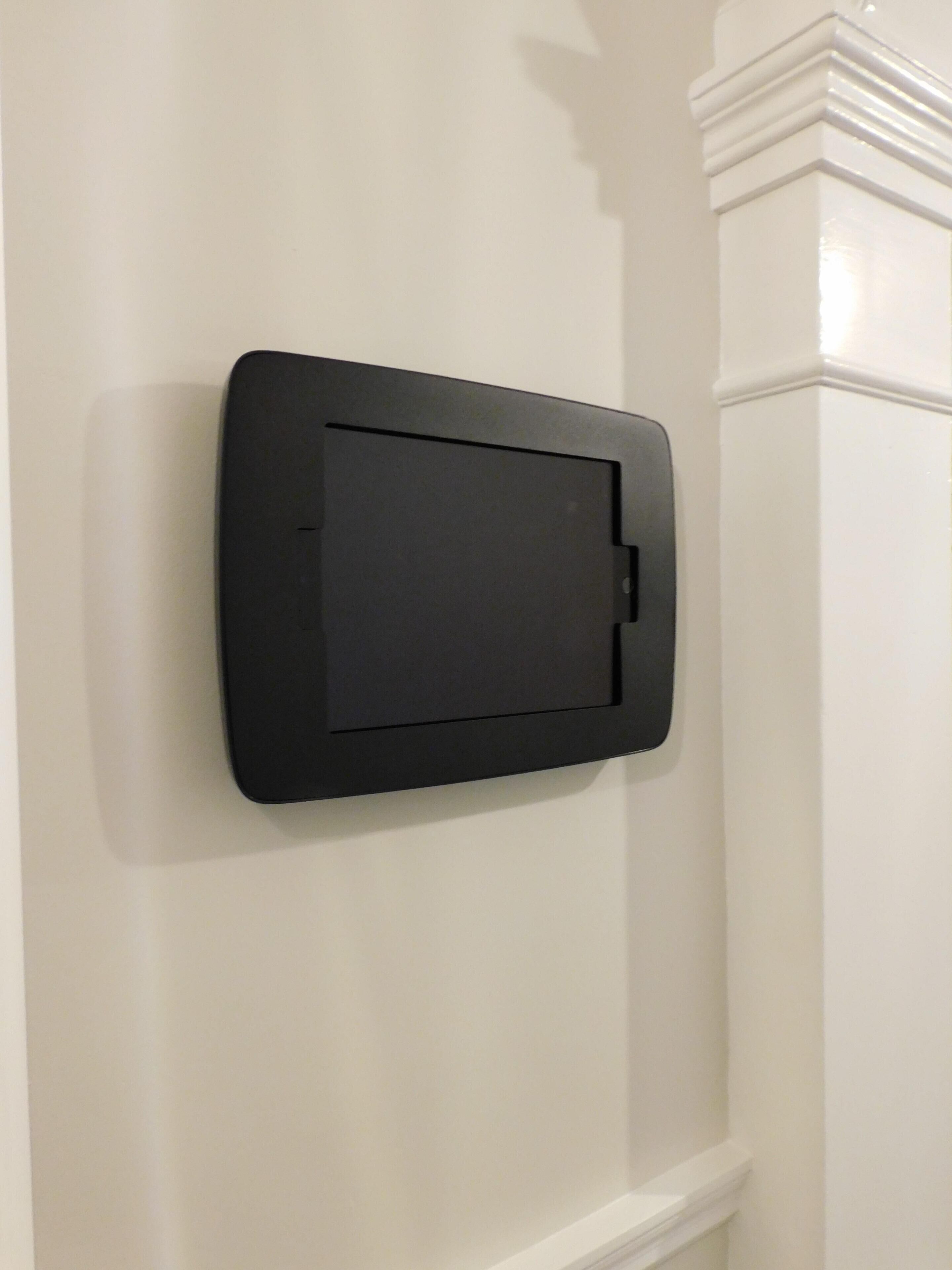 A black, rectangular object mounted on a white wall with a decorative molding at the top.