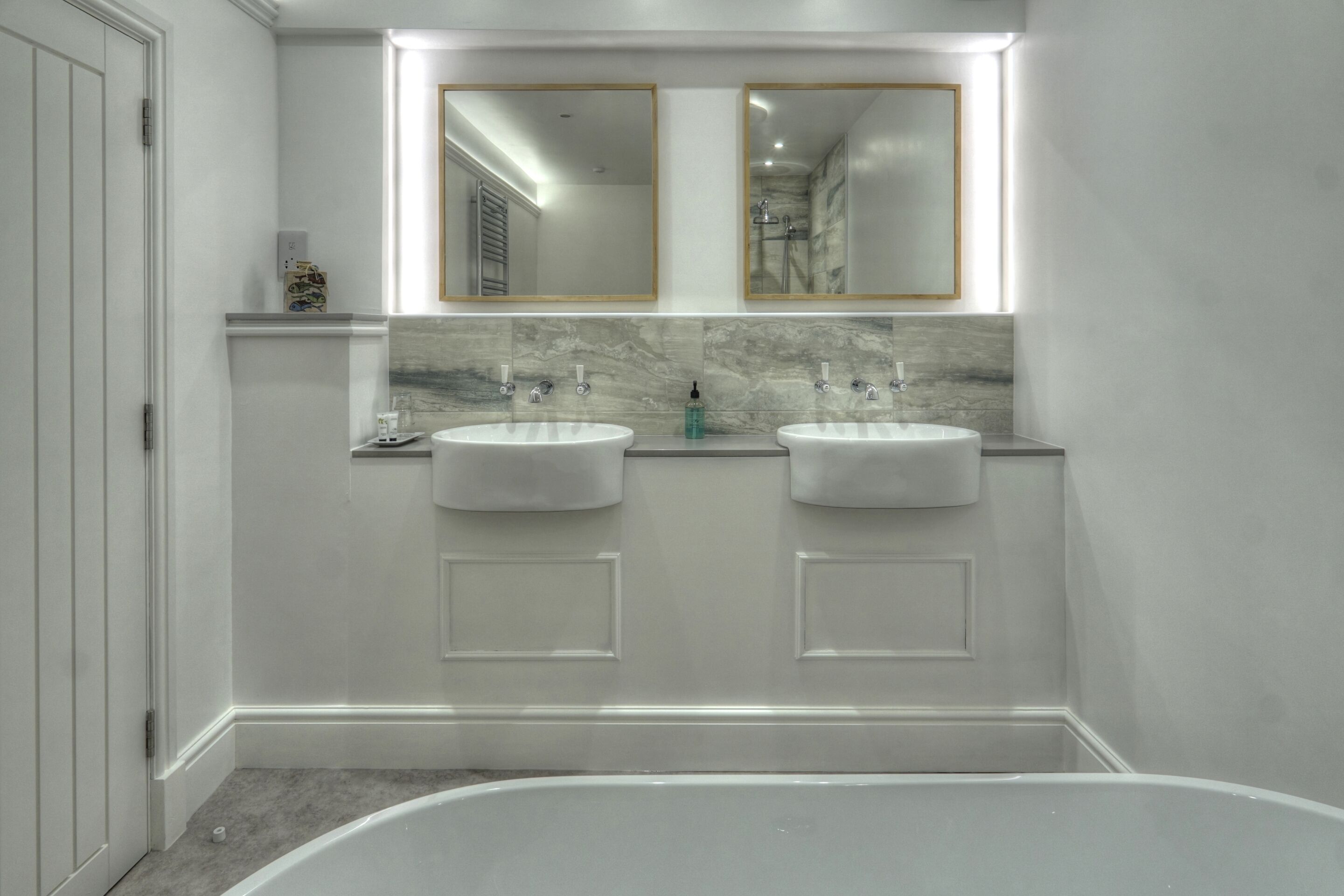 A modern bathroom with two sinks, a large bathtub, and a mirror above the sinks.