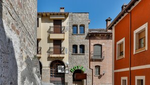 Un carrer estret amb un edifici de pedra i la façana que diu "HOTEL" al centre.