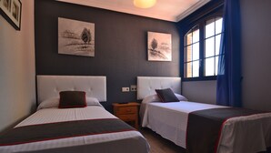 Habitació d'hotel amb dos llits, una tauleta de nit i obra d'art a la paret.