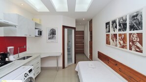 Une petite chambre comprenant un lit, un lave-linge, un four à micro-ondes et un évier.