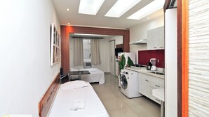 Une chambre d’hôtel équipée d’un lit, d’une machine à laver, d’une kitchenette et d’une salle de bain.