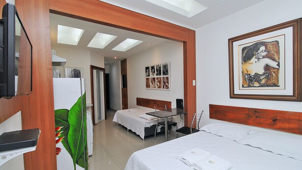 Une chambre d’hôtel avec un lit, un bureau, une chaise, une télévision et un tableau au mur.