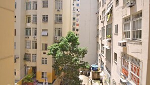 Un immeuble résidentiel à plusieurs étages, doté de balcons, de climatiseurs et d’un arbre au premier plan.