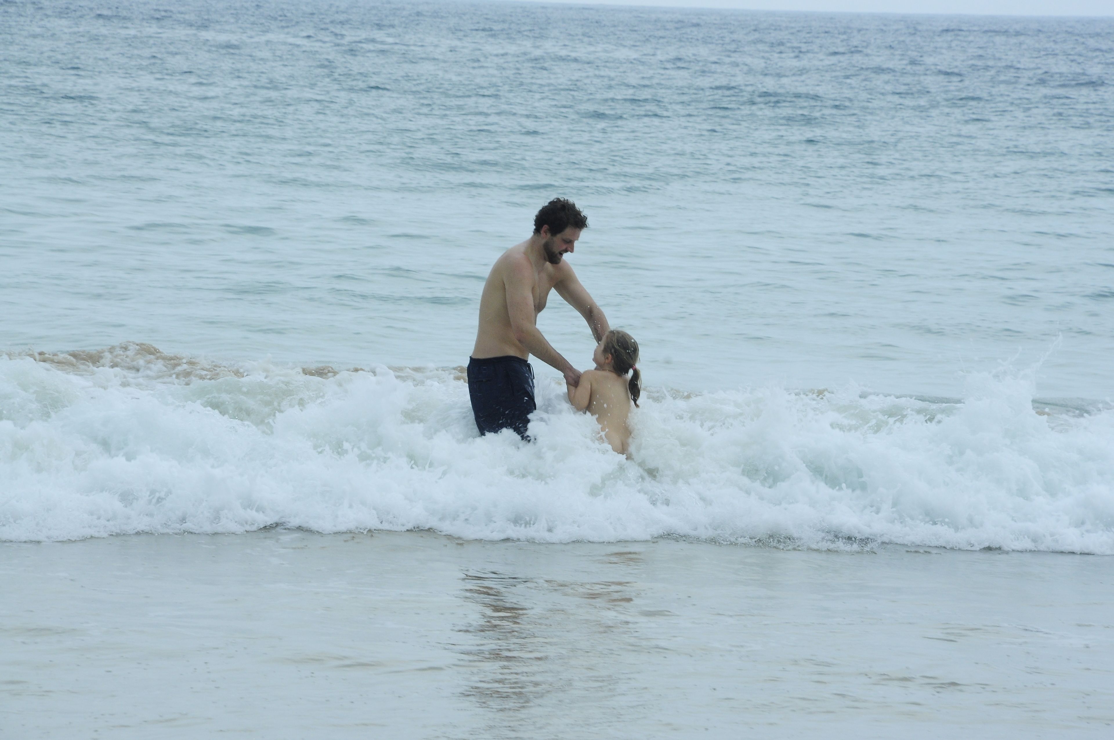 Escena de playa con olas y una persona en el agua.