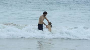 Escena de playa con olas y una persona en el agua.