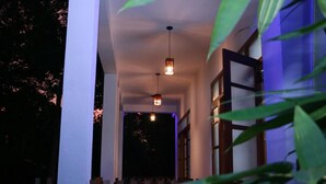 A hallway with a wooden fence, a hanging light fixture, and a window with a view of the outside.
