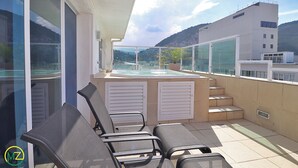 Eine Dachterrasse mit Pool, Liegestühlen und Blick auf die Stadt.